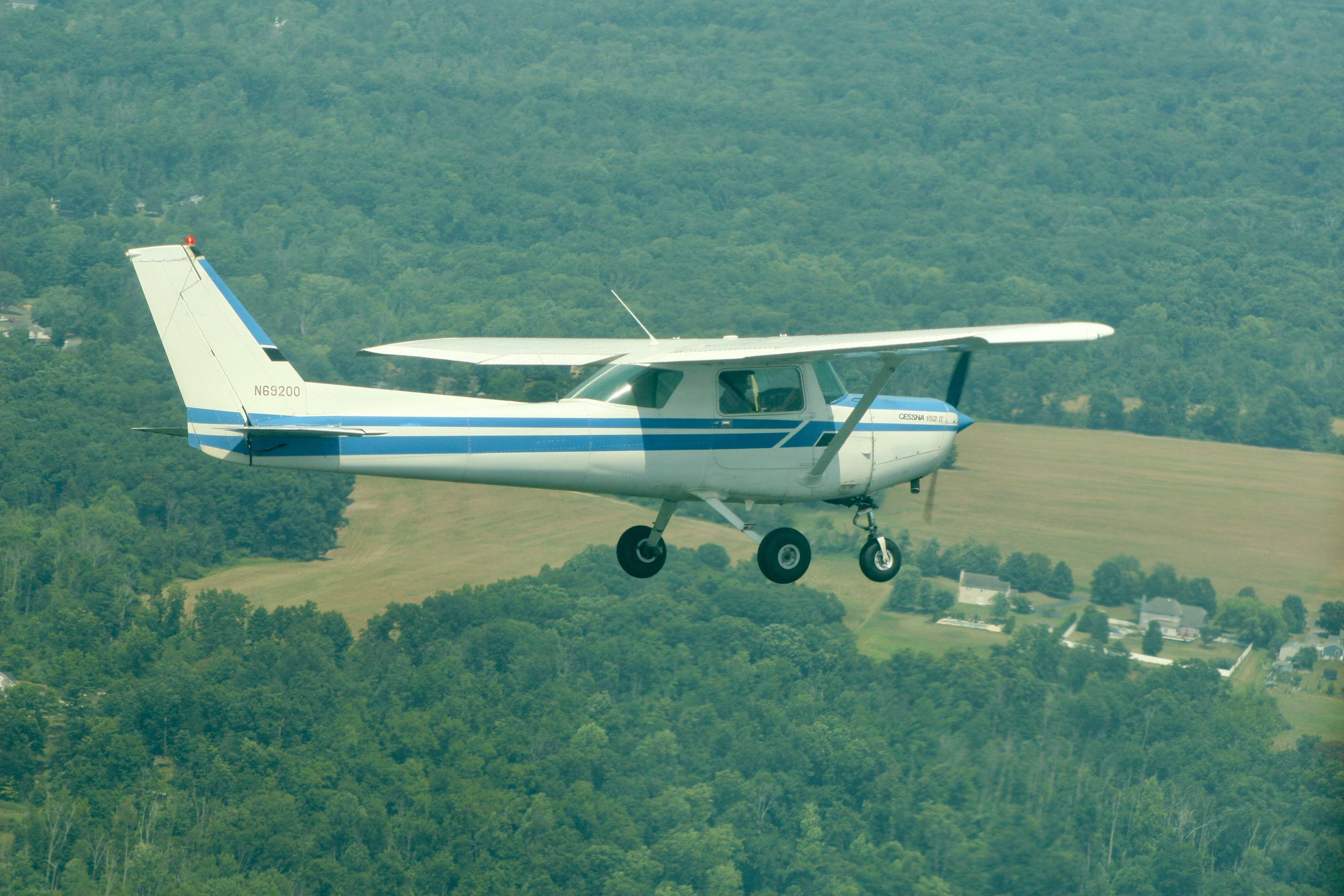 Pitcairn Flight Academy Cessna 152 flying over fields and forest near Pottstown, PA