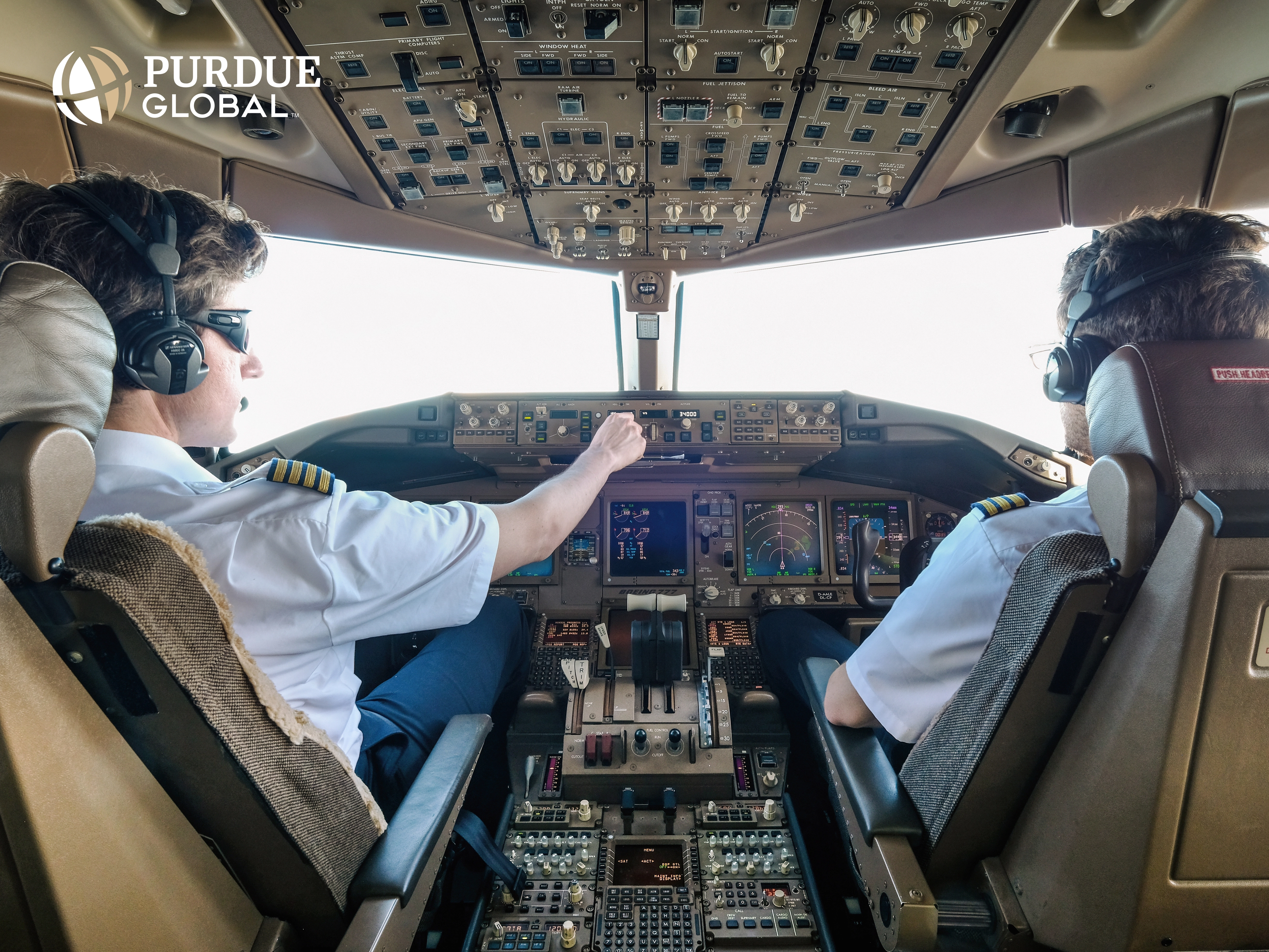 Commercial airline pilots in a commercial airline cockpit with a view of the sky and clouds outside the window