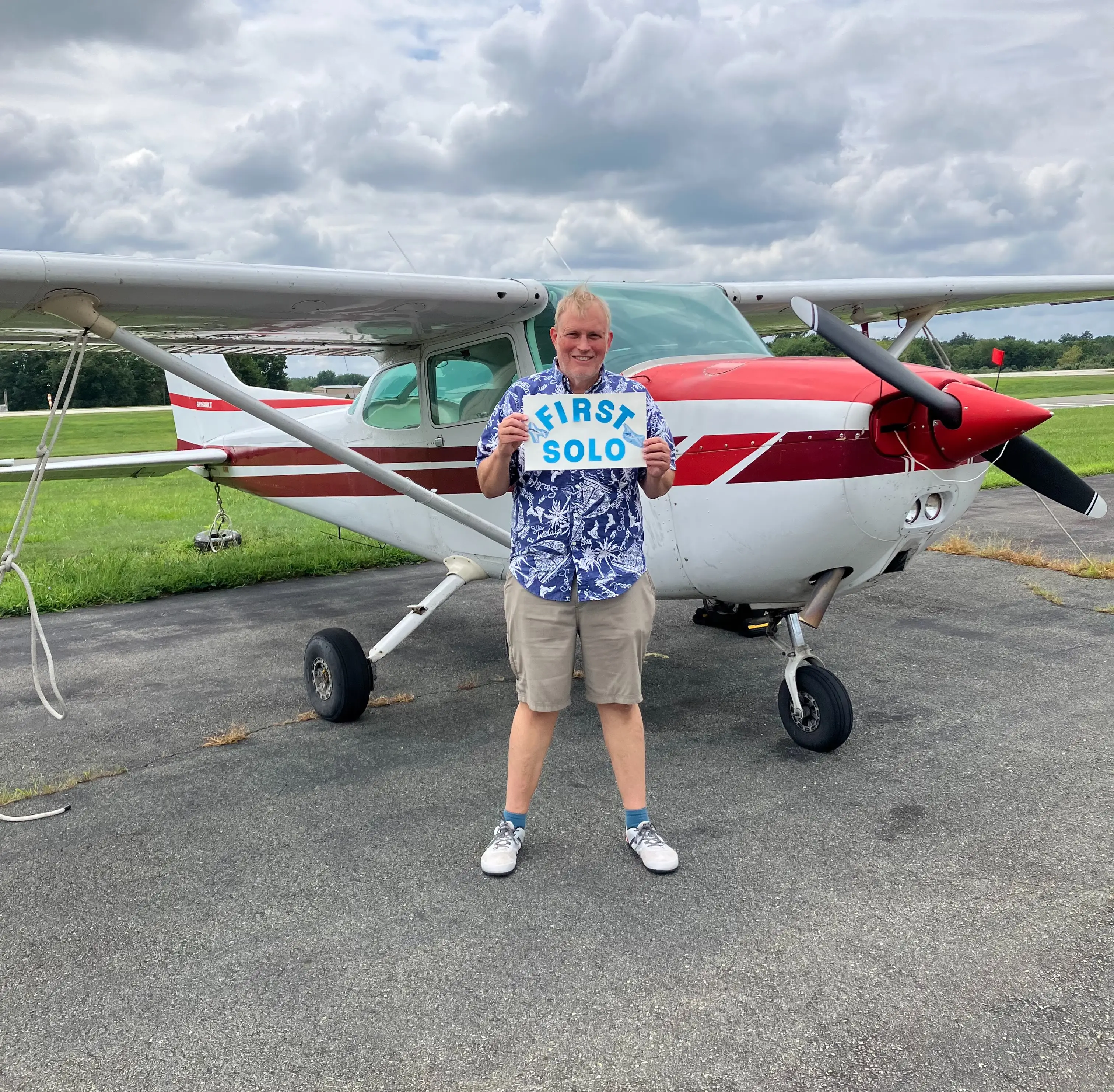Student pilot holding a first solo plate outside Pitcairn Flight Academy, Pottstown, PA