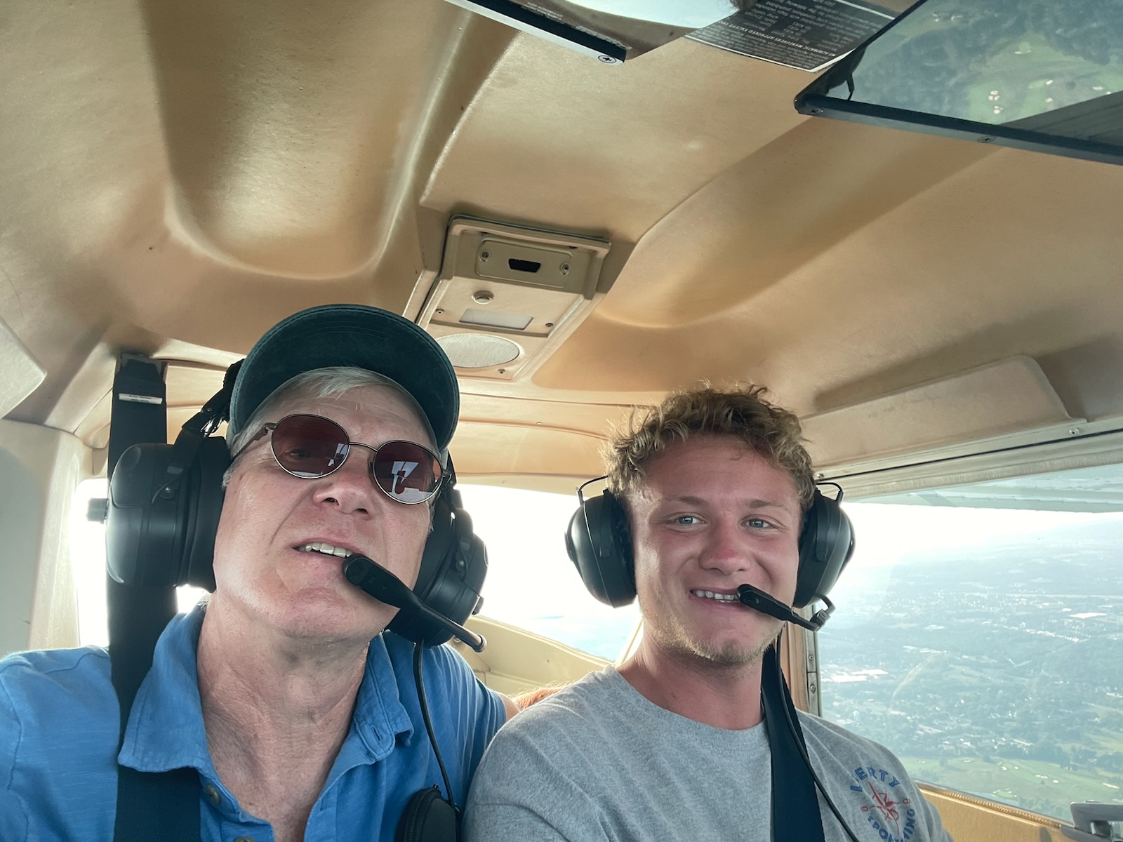 An instructor and a student smiling in headsets in the cockpit during a flight