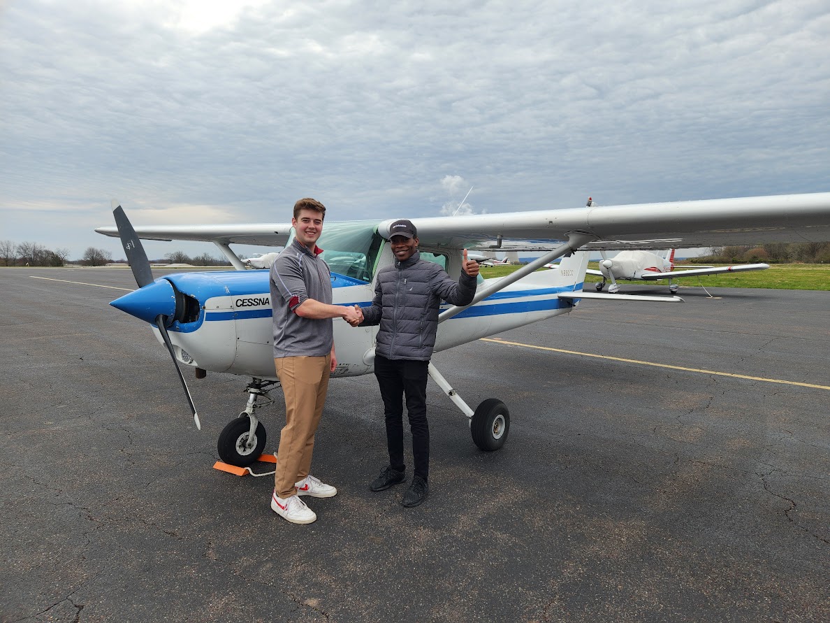 Two men shaking hands in front of a blue-and-white Cessna on the ramp